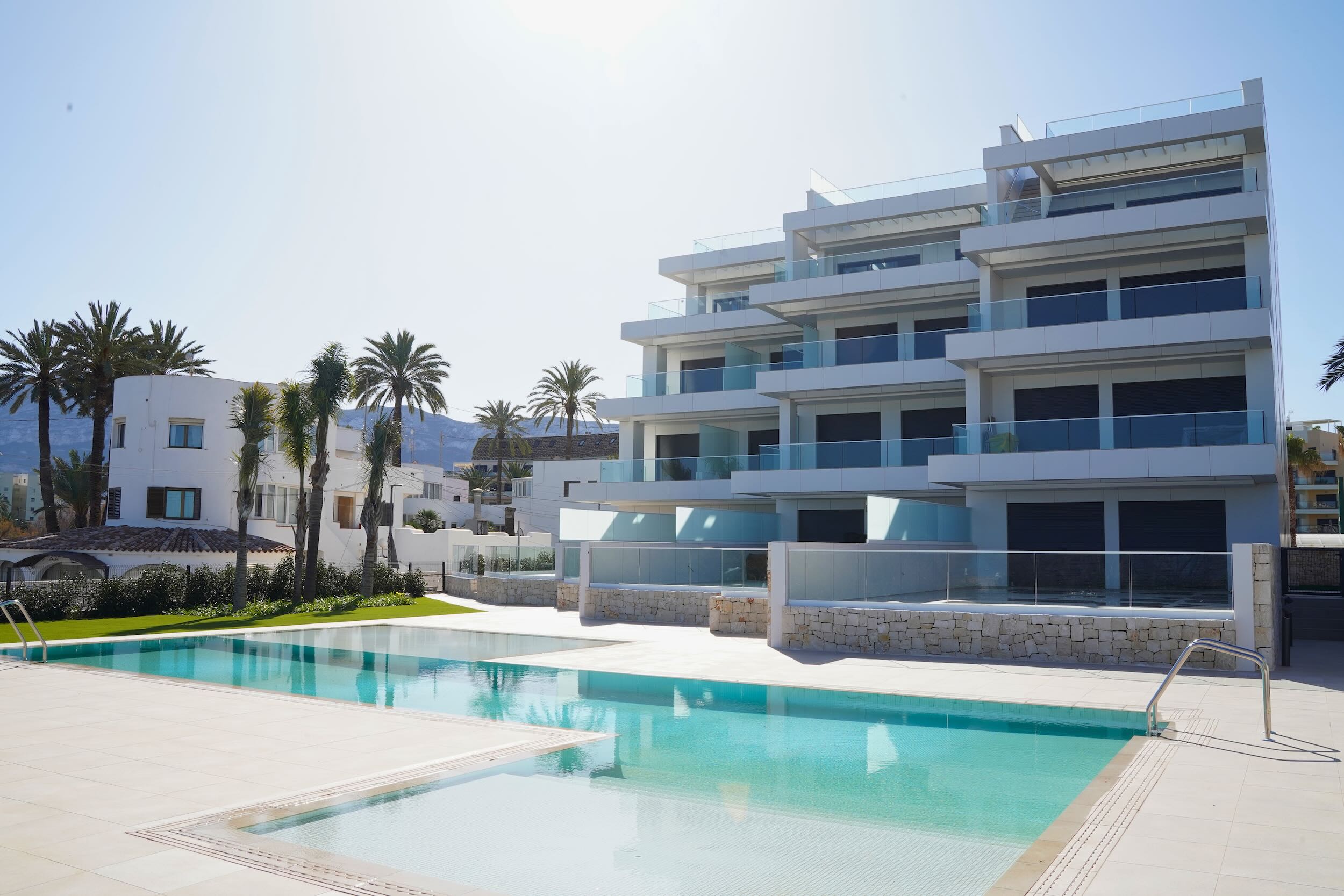 Edificio de apartamentos de obra nueva con piscina comunitaria y palmeras en la Costa Blanca